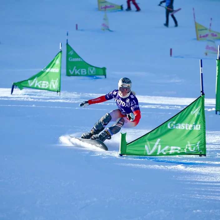 Ein Snowboarder fährt im Slalom um eine VKB-Flagge herum