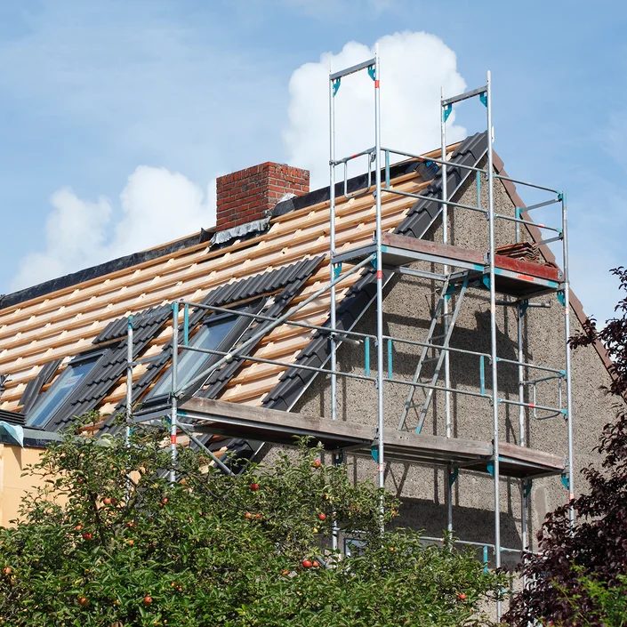 Foto eines älteren Hauses, das gerade saniert wird, es ist ein Gerüst davor aufgebaut.