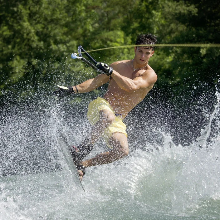 Foto von Alex Gschiel bei einem Stunt mit seinem Wakeboard im Wasser.